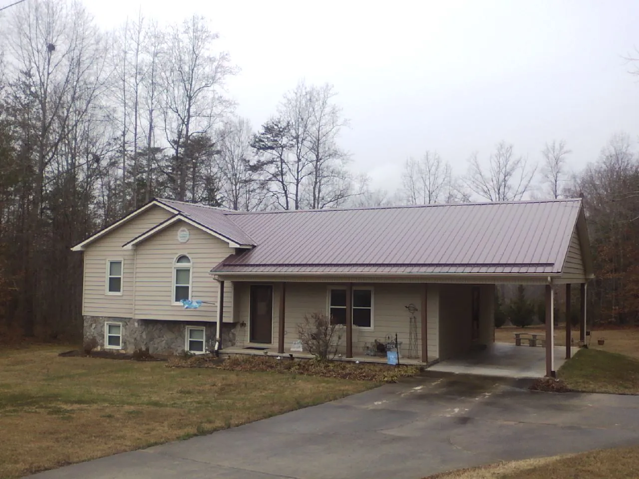 Burgundy metal roof on a tan split level home with an attached carport in Osceola